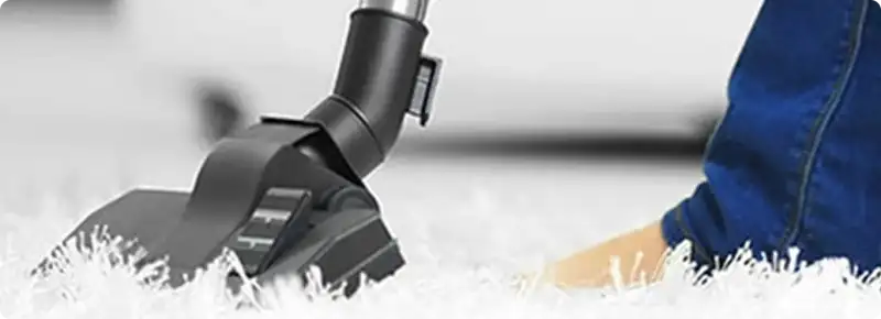 Close-up of a professional vacuuming a white carpet in Palm Beach.