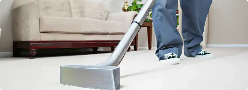 Carpet cleaning technician using a hot-water extraction wand on a light-colored carpet in a living room, West Palm Beach, FL.